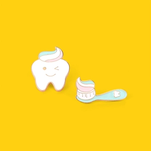 Detail of creative cartoon tooth and toothbrush enamel pins on a vibrant yellow background