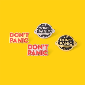 Fashionable enamel letter brooches and planet badges on bright yellow background