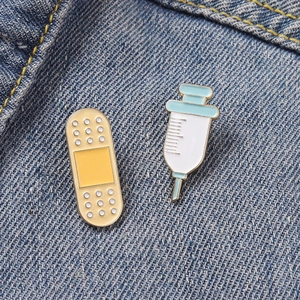 Détail de broches en émail pansement et seringue sur fond de tissu en denim