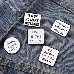 Détail d'un lot de 5 épingles en émail minimalistes avec citations sur denim