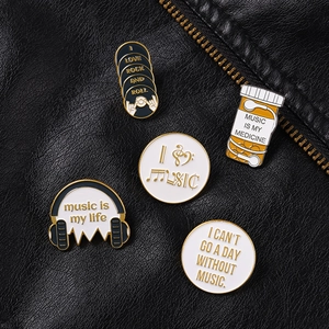 Detail view of five music-themed enamel pins on a black leather jacket with golden zipper
