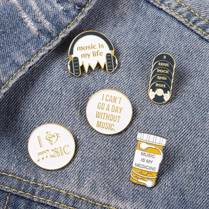 Music-themed enamel pin set with headphones and record designs on denim background