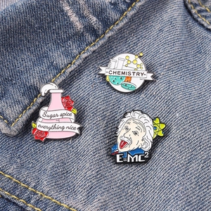 Three-piece science enamel pin set featuring Einstein and chemistry theme on denim fabric