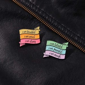 Détail de pin's en émail colorés avec phrases motivantes sur une veste en cuir noir