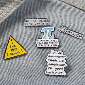 Detailed close-up of a 5-piece math and engineering enamel pin set on denim fabric