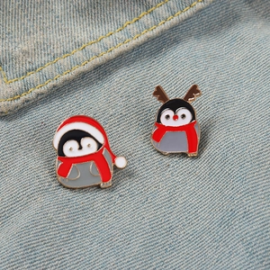 Détail de pin's pingouin de Noël en émail avec bonnet et bois sur tissu denim
