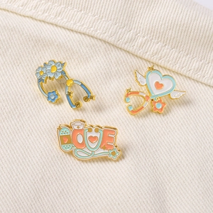 Detailed view of three medical enamel pins featuring LOVE letters and stethoscopes