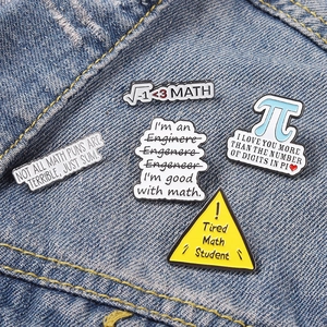 Detail of five math-themed enamel pins displayed on blue denim fabric texture