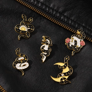 Set of five mystical enamel snake brooches featuring sun, dagger, and skull motifs on a jacket