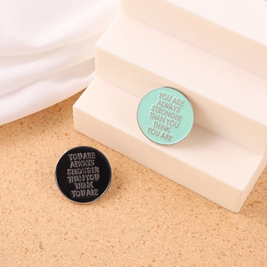 Detailed macro view of black and mint green enamel letter pins on a minimalist podium