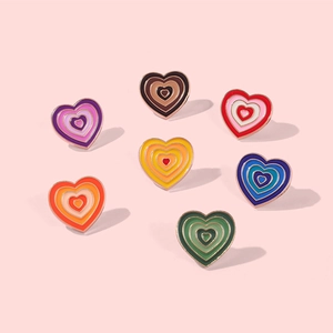 Flat lay macro of colorful heart-shaped enamel brooches with golden metal outlines