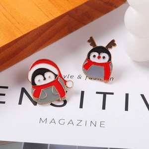 Broches de Noël en émail avec d'adorables pingouins festifs posées sur un magazine de mode