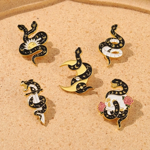 Detail of five dark aesthetic snake enamel pins featuring moon, star, and skull motifs