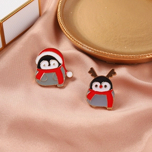 Détail de broches pingouins de Noël en émail avec bonnets festifs sur de la soie