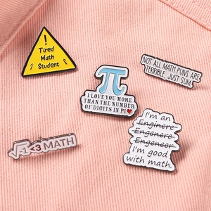 Detailed macro view of five math-themed enamel pins on a soft pink fabric background