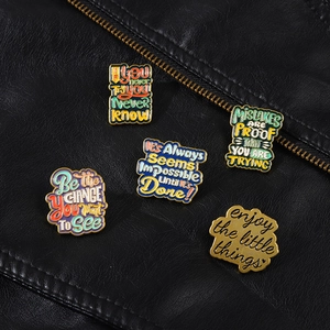 Détail de broches en émail vintage avec texte inspirant sur fond de cuir noir texturé