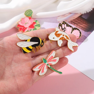 Emaille speldjes set met bijen en libellen op roze zijden achtergrond voor decoratie