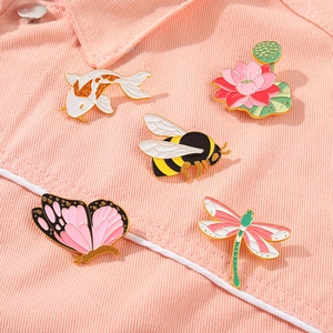 Detailweergave van insecten emaille spelden set op een roze spijkerjasje met een bijtje