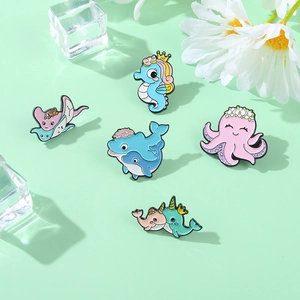 Vue à plat de cinq broches émaillées colorées d'animaux marins sur fond vert clair