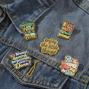 Détails de cinq pin's émaillés colorés sur le revers d'une veste en jean bleue