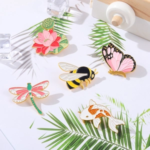 Set van vijf emaille insectenbroches met bij, lotus en vlinder op een witte achtergrond