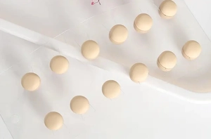 Detail view of cream magnetic scarf clips arranged neatly on a white display board