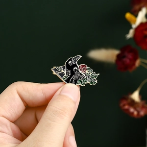 Detail of Gothic crow and red rose enamel brooch with gold metal edges and black finish