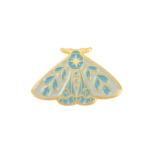 Détail macro d'une broche papillon en émail avec motifs célestes d'étoiles et de lune