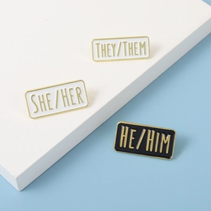 Detailansicht der rechteckigen Emaille-Pronomen-Pins mit vergoldetem Rand und Glanz-Finish