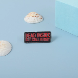 Macro detail of rectangular enamel pin with Dead Inside But Still Horny text engraving