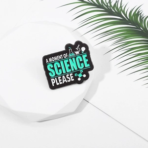 Close-up of science enamel pin with microscope icons on a clean white display stand