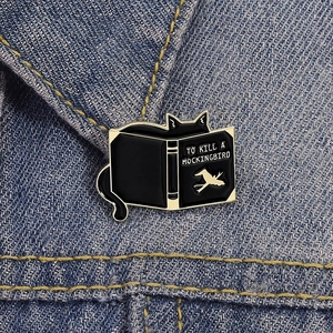 Détail du pin's chat noir et livre To Kill a Mockingbird sur veste en jean