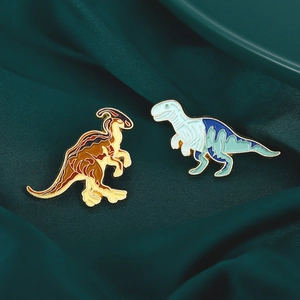 Detailed macro view of two colorful dinosaur enamel pins on green silk fabric background