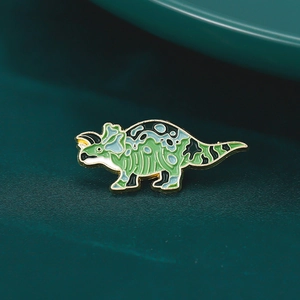 Close-up of triceratops enamel pin with green camouflage pattern and golden edges
