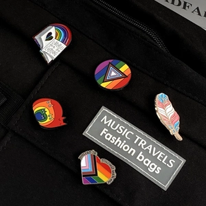 Detailaufnahme von bunten Regenbogen-Emaille-Pins an einer schwarzen Segeltuchtasche