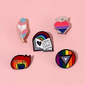 Detail von fünf Regenbogen Emaille Pins mit Büchern und Herzen auf rosa Hintergrund