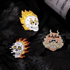 Trois pin's en émail style punk avec crânes, feu et fumée sur un fond sombre élégant