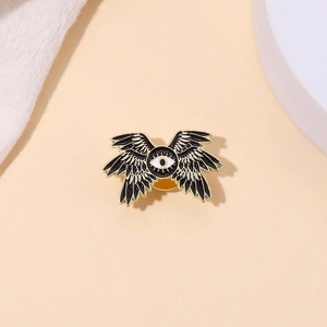 Macro shot of dark eagle eye brooch with black enamel wings and gold metal plating