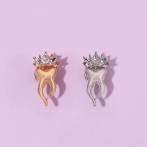 Détail de broches en forme de dent en argent et or rose avec couronnes en cristal