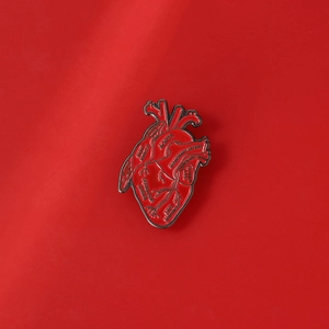 Makroaufnahme der roten anatomischen Herz-Emaille-Nadel mit detaillierter Aorta und Arterien