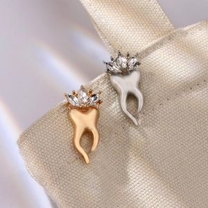 Broche créative en forme de dent avec couronne scintillante sur fond de toile beige
