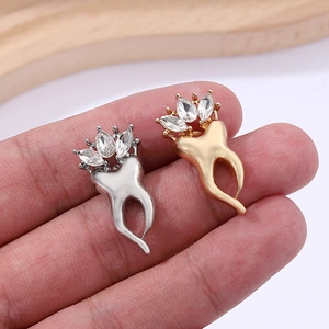 Gros plan de broches créatives en forme de dent or et argent avec détails de couronne