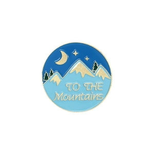 Detail of round enamel badge with mountains moon and TO THE Mountains text engraving