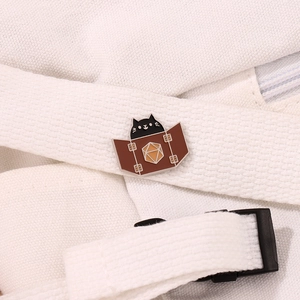 Cute black cat enamel pin with D20 dice design pinned on a white canvas bag