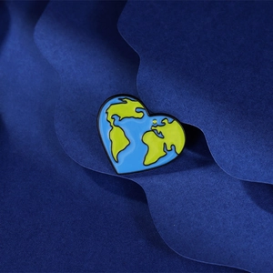 Heart-shaped earth map enamel brooch with blue oceans and green lands on blue background