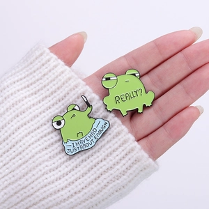 Funny green frog enamel pin set with witty text on a white knitted sweater sleeve