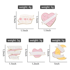 Dettaglio di cinque spille in smalto rosa e bianco con frasi motivazionali in inglese