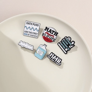 Macro view of six math themed enamel pins with geometric formulas on white ceramic tray