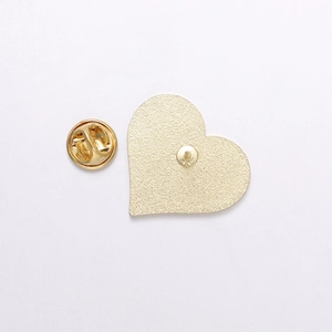 Detailed view of the gold heart-shaped enamel brooch with frosted metal back and butterfly clutch