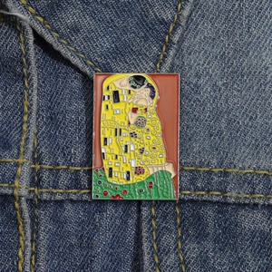 Broche en émail Le Baiser de Gustav Klimt sur fond de tissu en jean bleu